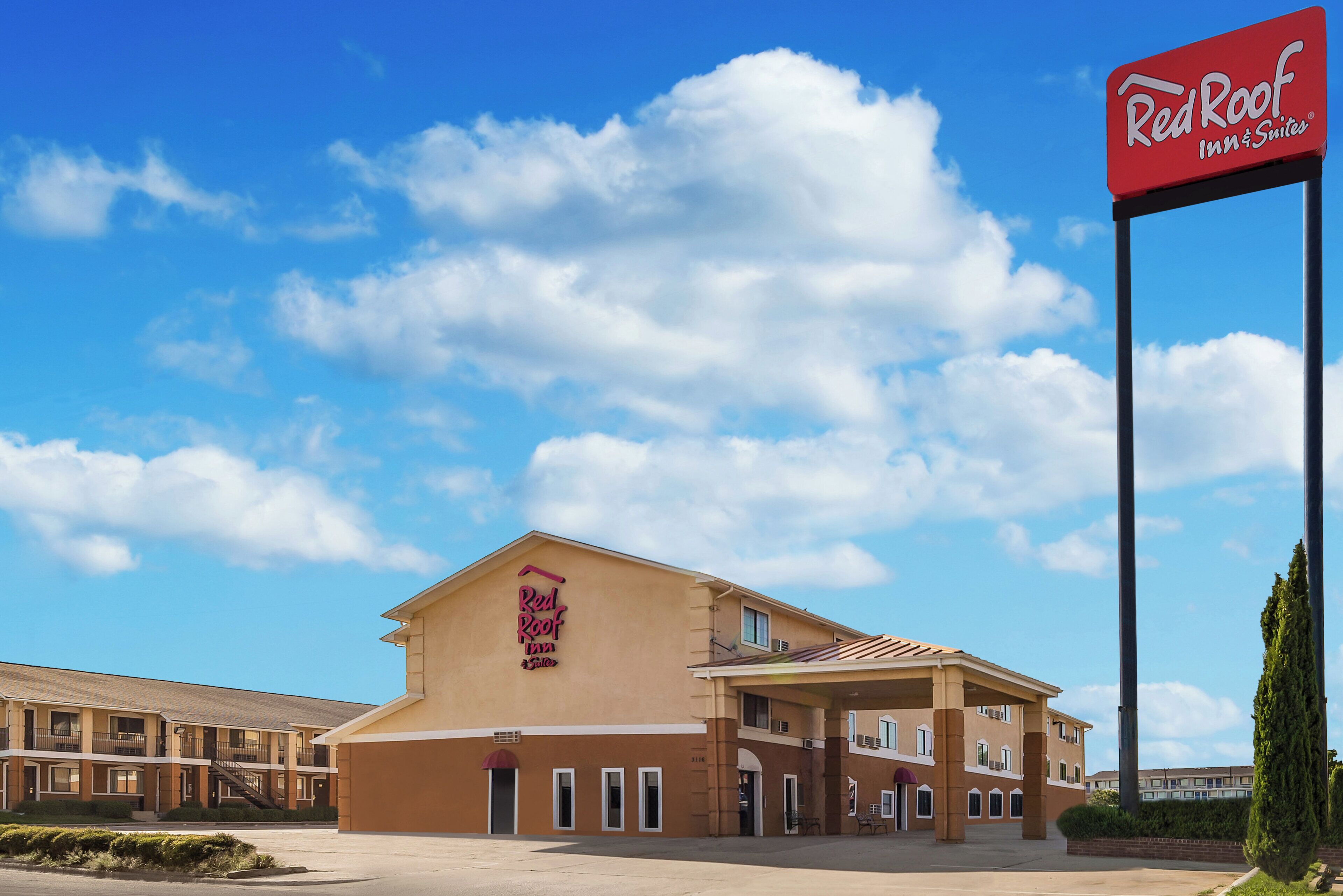 A Red Roof Inn & Suites building with a clear sky and clouds.