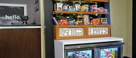 Un quiosco autoservicio con una variedad de aperitivos y bebidas, incluyendo papas fritas, galletas y bebidas embotelladas.