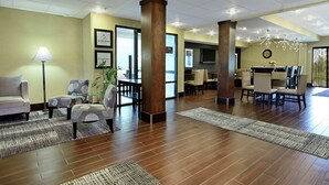 Een hotel lobby met een receptiebalie, een zithoek en een eetgedeelte.