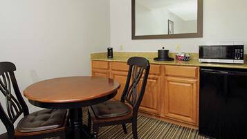 A compact kitchen with a dining table, chairs, a microwave, and a dishwasher.