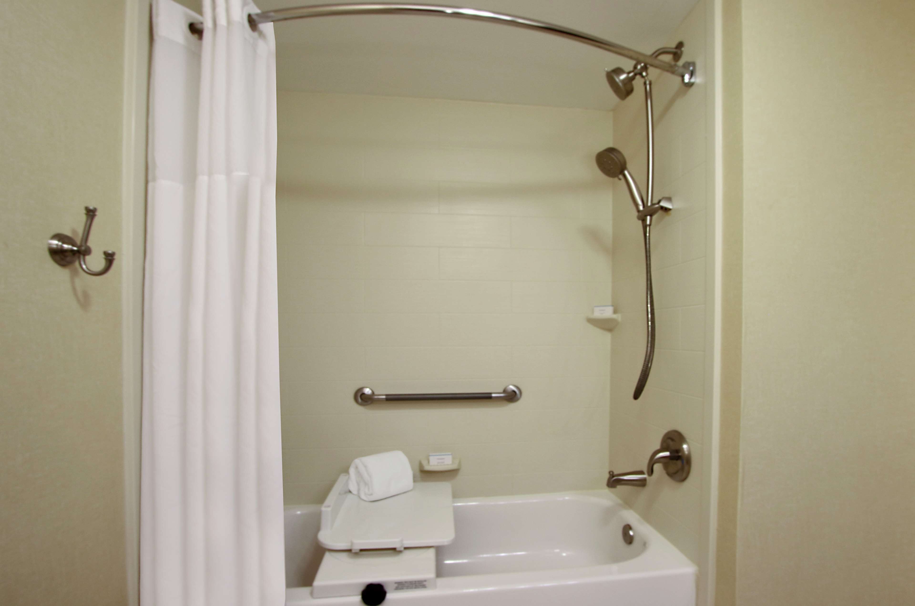 A bathroom with a bathtub, a shower, a grab bar, and a towel rack.