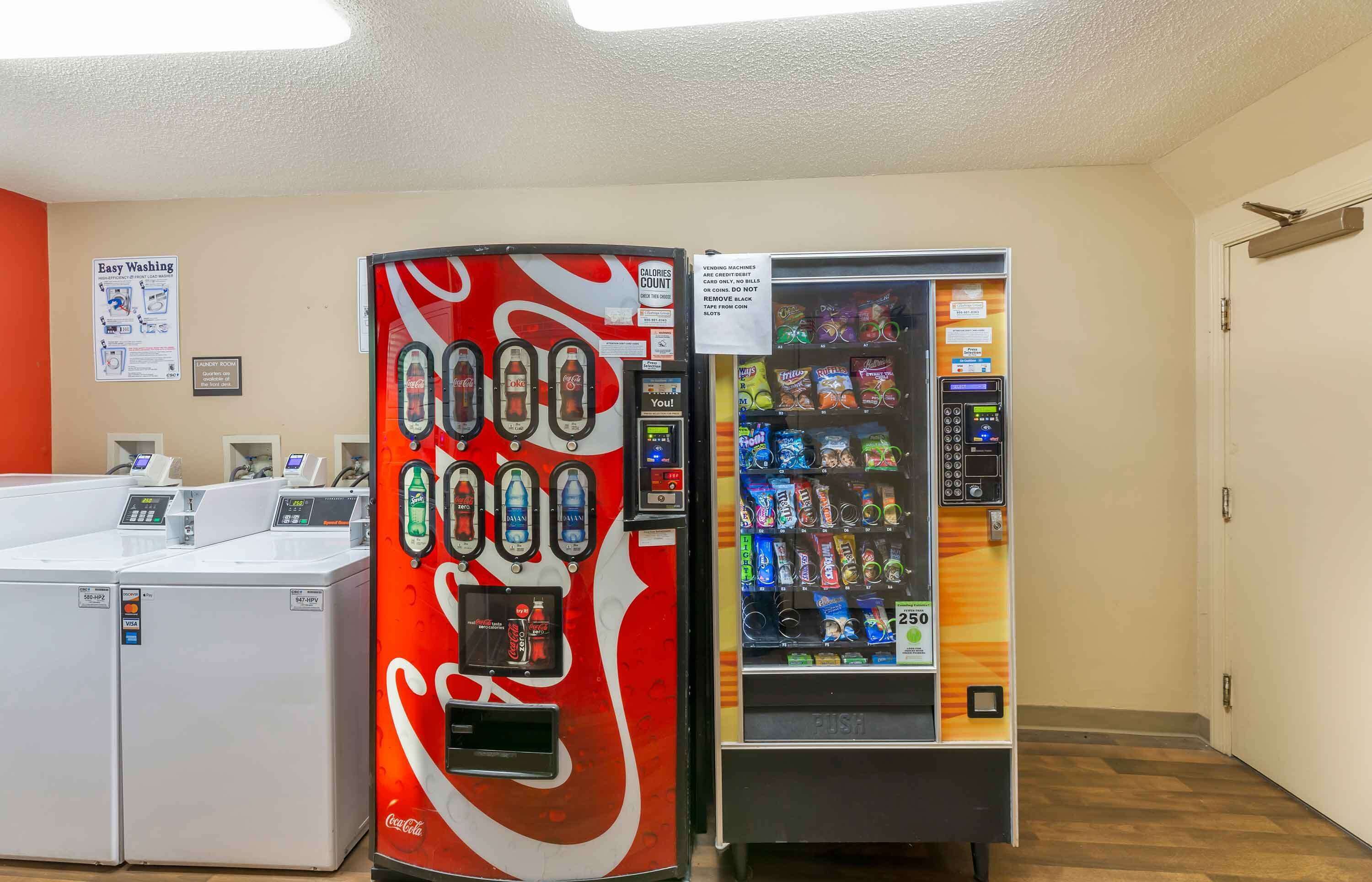 A laundromat with a Coca-Cola branded machine and a vending machine.