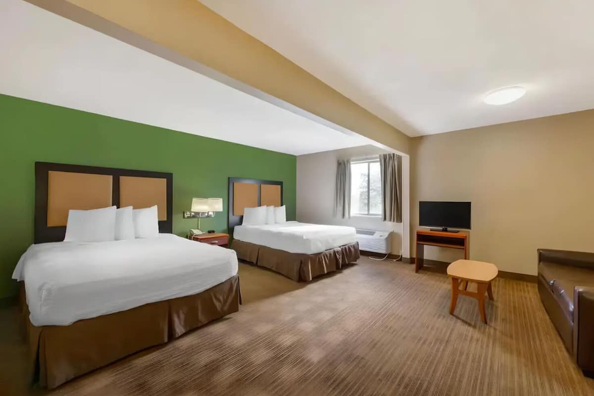 Ett hotellrum med två sängar, en TV, ett skrivbord och ett fönster.
