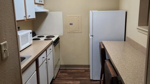 A compact kitchen with white cabinets, a microwave, stove, and a refrigerator. - Suburban Studios Columbus - Dublin (Dublin)