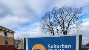 A sign for Suburban Studios with a blue background and a stylized mountain graphic. - Suburban Studios Columbus - Dublin (Dublin)