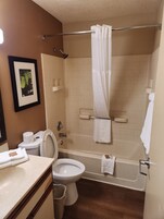 Un baño con inodoro, lavamanos, bañera y cortina de ducha.