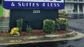 A sign for 'STUDIOS & SUITES 4 LESS' with a large logo and the address '2222'.