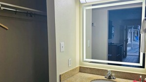 A bathroom with a granite countertop sink, a mirror, and a towel rack.
