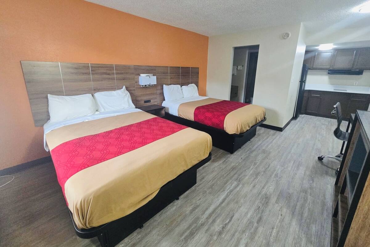 Een hotelkamer met twee bedden, een kitchenette en een badkamer.