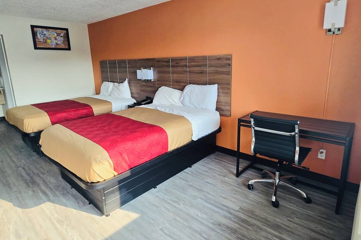 Een hotelkamer met twee bedden, een bureau en een stoel.