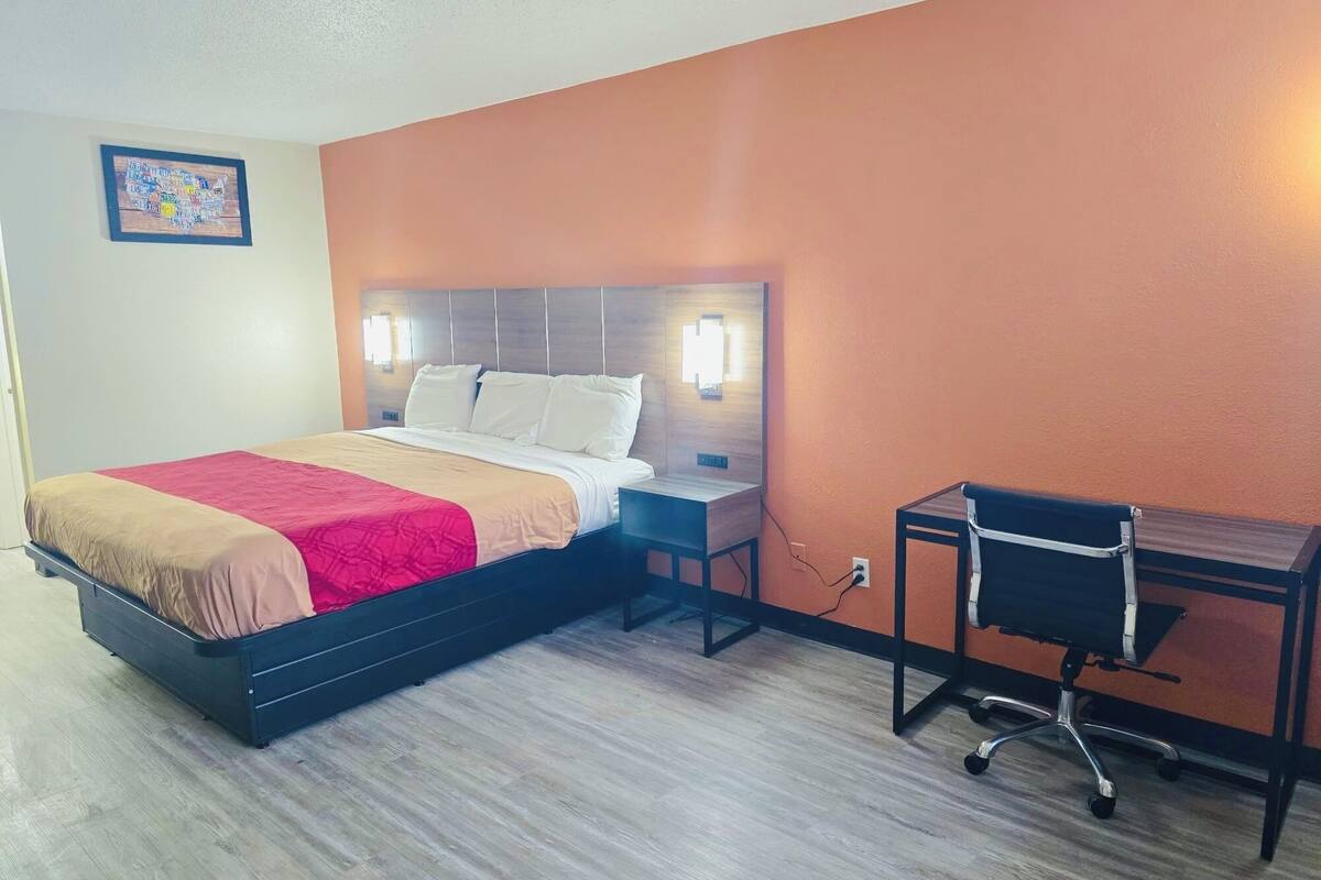 Een hotelkamer met een bed, nachtkastje, bureau en stoel.