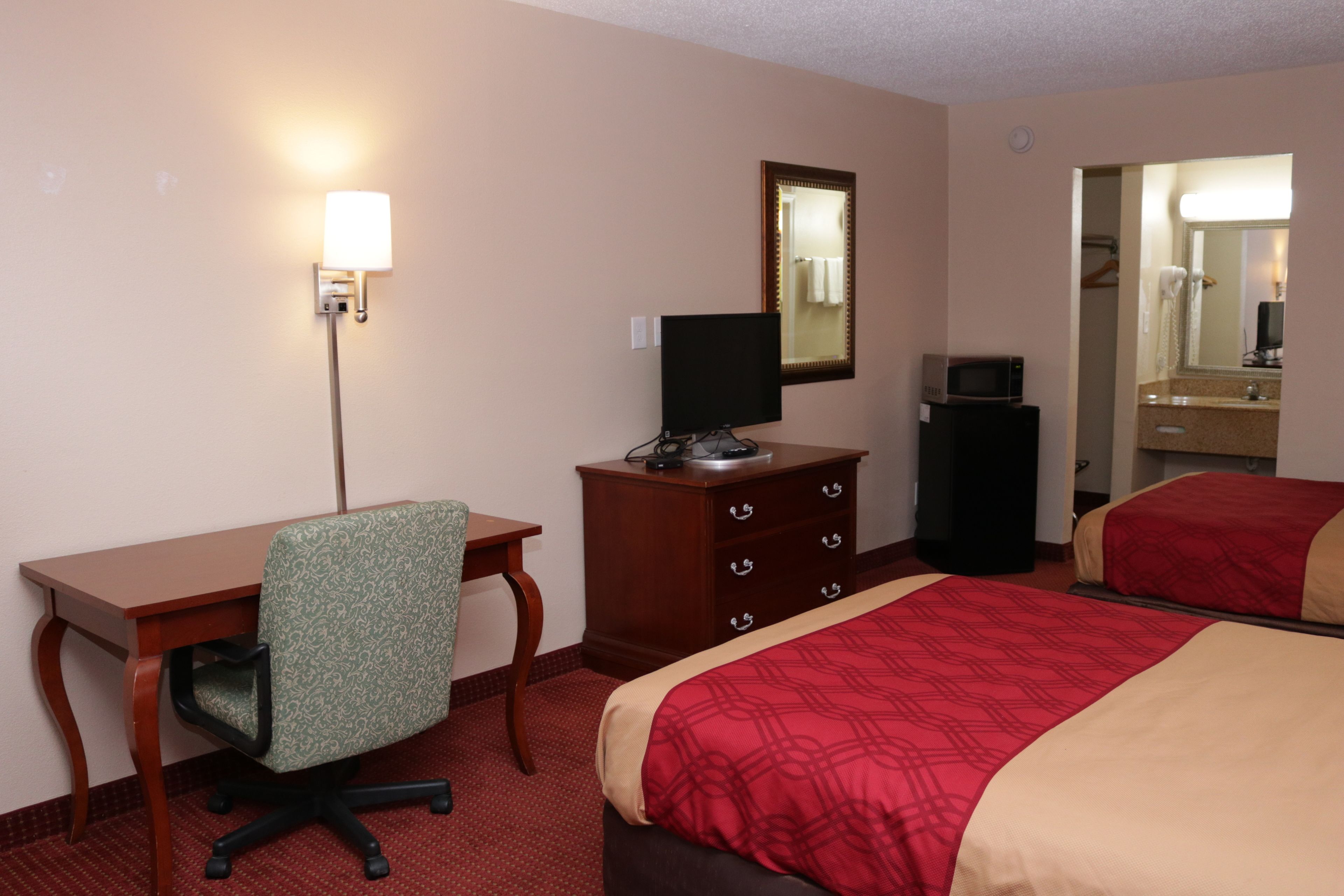 Ein Hotelzimmer mit Schreibtisch, Stuhl, Kommode und zwei Betten.