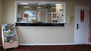 A reception area with a counter, a phone, a no smoking sign, and a wall-mounted notice board.