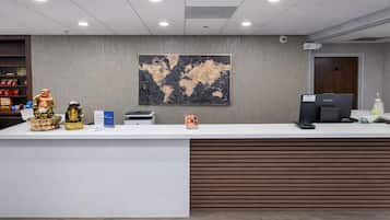 A reception desk with a world map, a printer, and a Lenovo computer.