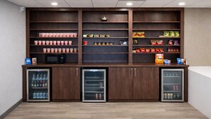 A kitchenette with a microwave, refrigerator, and shelves stocked with snacks and beverages. - Best Western Cy-Fair (Houston)