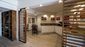 A modern kitchen with wooden cabinets, a dining area with chairs, and artwork on the walls. - Red Roof Inn PLUS+ Houston - Energy Corridor (Houston)