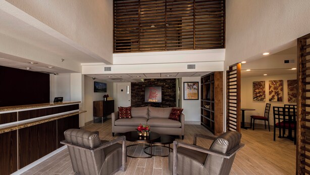 A spacious lobby with a high ceiling, a reception desk, a seating area with a sofa and chairs, and a staircase leading to an upper level. - Red Roof Inn PLUS+ Houston - Energy Corridor (Houston)