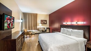 A hotel room with a large bed, a desk with a chair, a television, and a desk lamp. - Red Roof Inn PLUS+ Houston - Energy Corridor (Houston)