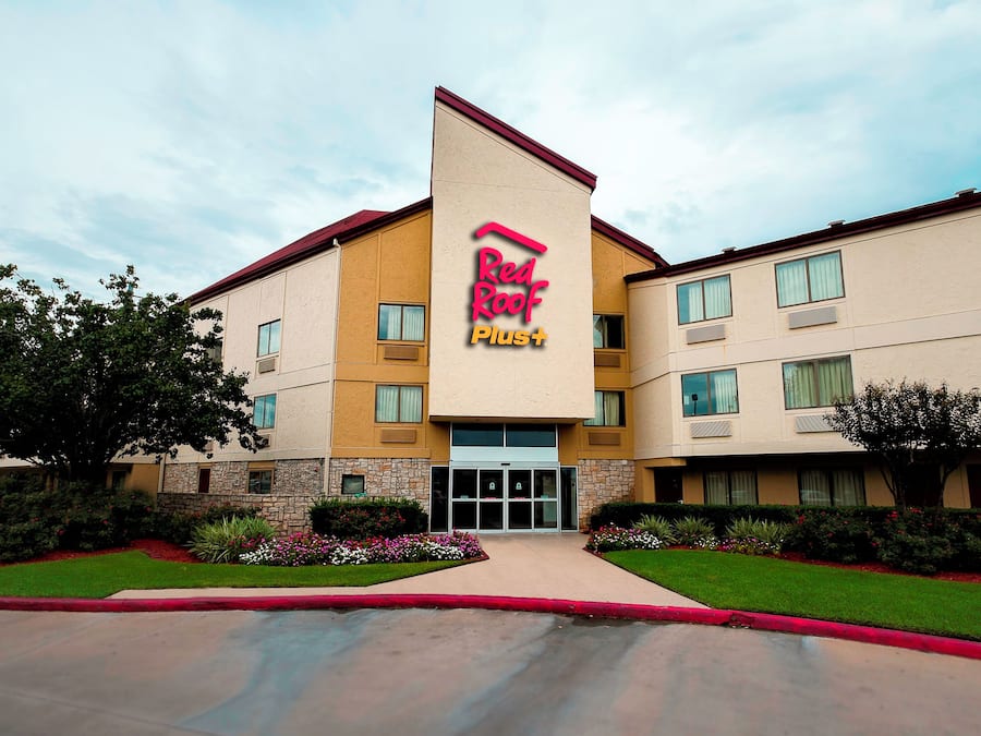 Un hotel Red Roof Plus con un diseño moderno, que cuenta con una entrada destacada y un exterior bien cuidado.