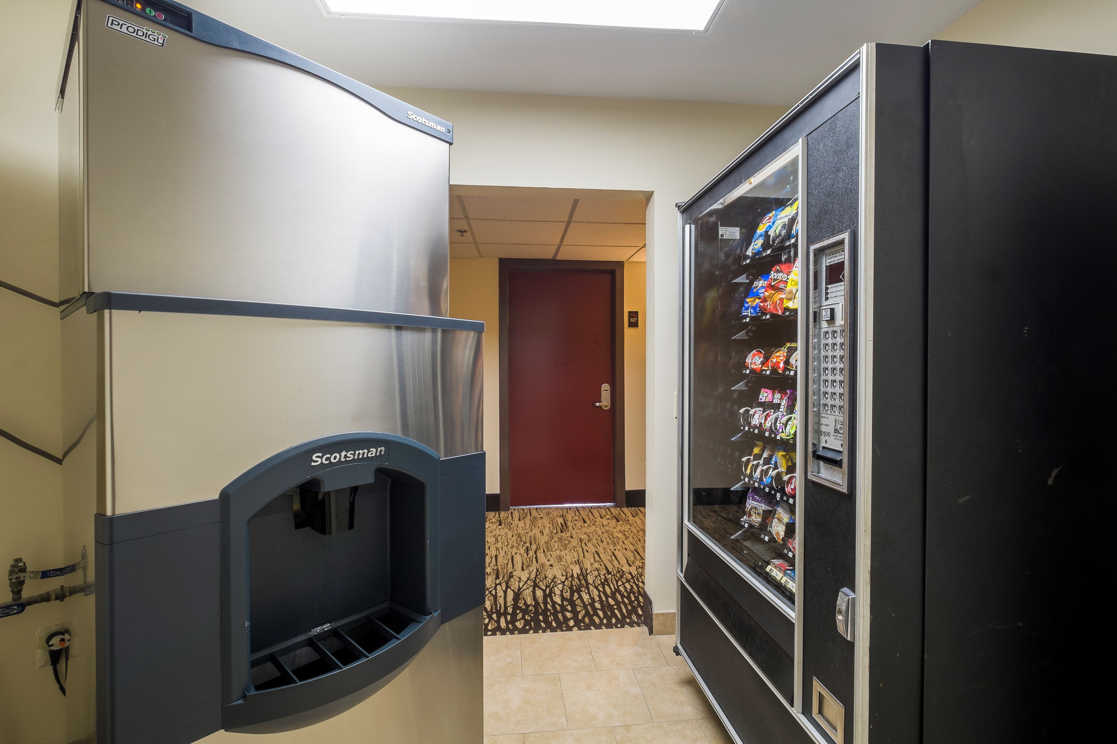 A hallway with a vending machine stocked with snacks and a water dispenser.