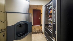 A hallway with a vending machine stocked with snacks and a water dispenser. - Red Roof Inn PLUS+ Houston - Energy Corridor (Houston)