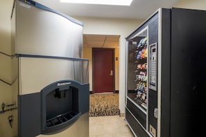 A hallway with a vending machine stocked with snacks and a water dispenser. - Red Roof Inn PLUS+ Houston - Energy Corridor (Houston)