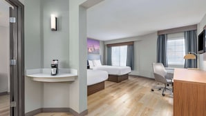 Une chambre d’hôtel avec deux lits, un bureau, une chaise, une télévision et une machine à café.