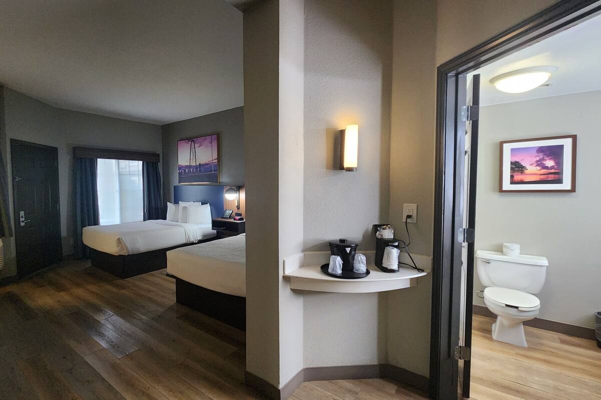 Habitación de hotel con cama, mesita de noche, ventana y baño con inodoro y lavabo.