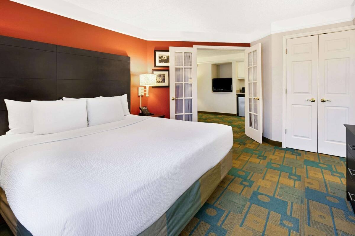 Habitación de hotel con una cama grande, un escritorio, una silla, un teléfono, una lámpara y un armario.