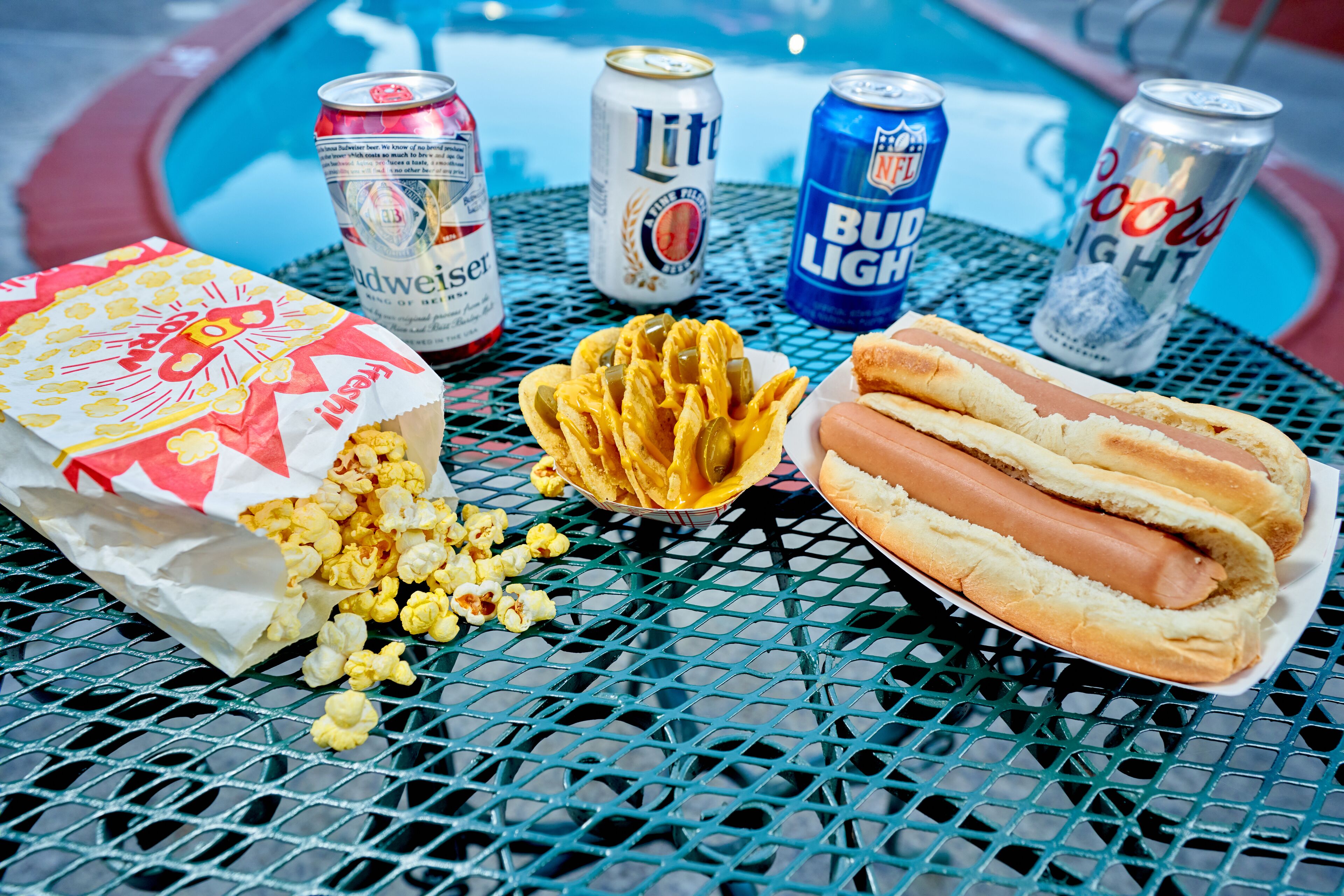En bord med en hotdog, popcorn og tre øl.