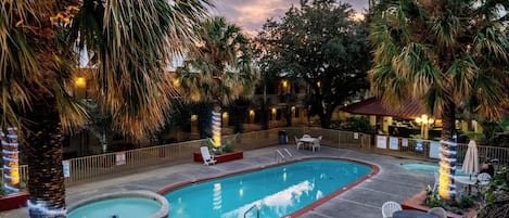 Une piscine entourée d’une terrasse, de palmiers et d’un espace salon extérieur.