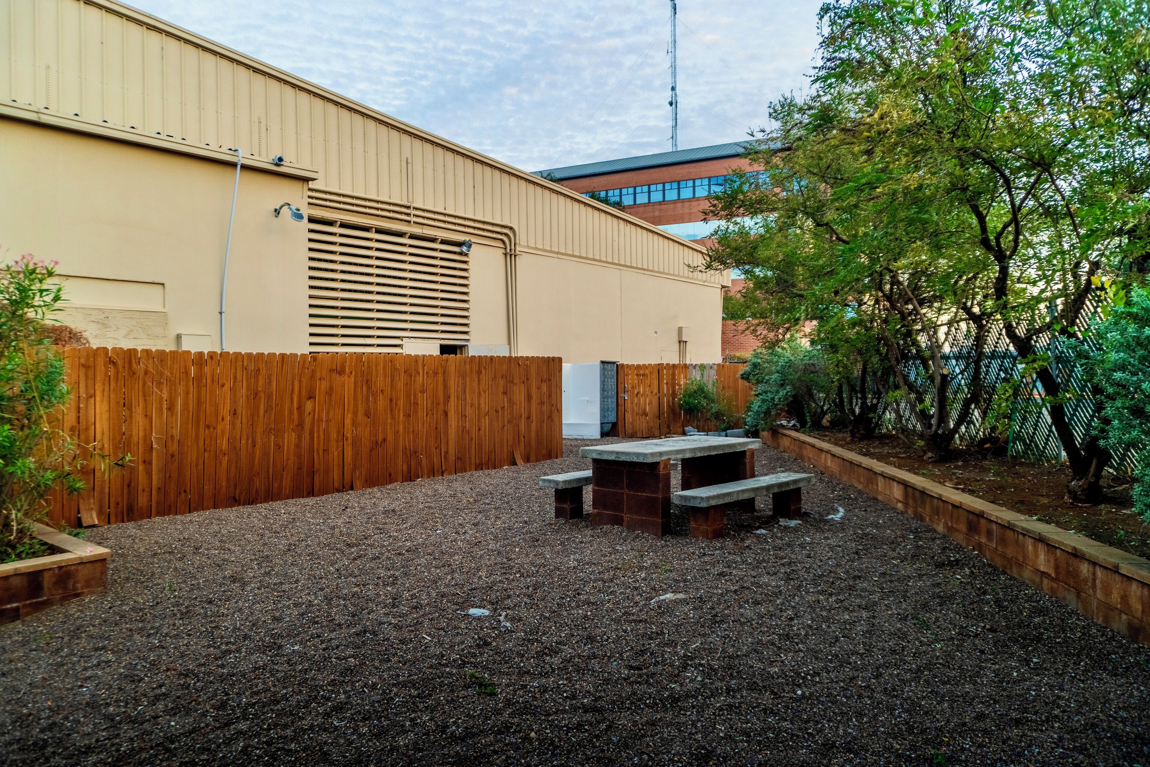 A backyard with a wooden fence, a gravel area, and a picnic table.