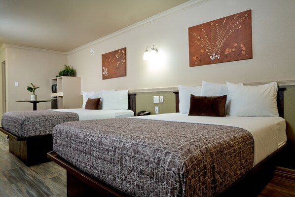 Two beds with matching headboards and a large bed with an extended headboard, adorned with bedding and decorative wall art.