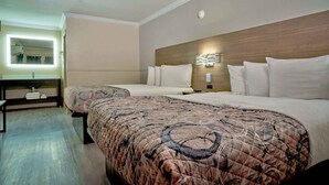 A hotel room with two beds, a bedside table, a mirror, and a wall-mounted light fixture. - Family Garden Inn & Suites (Laredo)