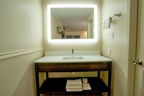 Bathroom features a sink, mirror, and towels, with a bathtub and door nearby.