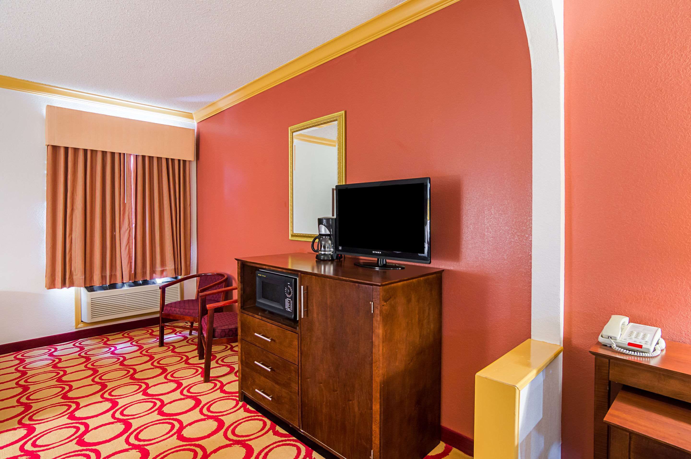 Habitació d'hotel amb un armari de fusta, televisió, telèfon i finestra amb cortines.