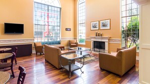 A spacious lounge with large windows, comfortable seating, a flat-screen TV, and a fireplace.