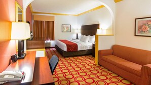 A hotel room with a bed, a sofa, a desk with a telephone, and a mirror.