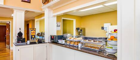 Ein Frühstücksbereich eines Hotels mit einem Buffet, einer Mikrowelle, einem Toaster und verschiedenen Speisen.