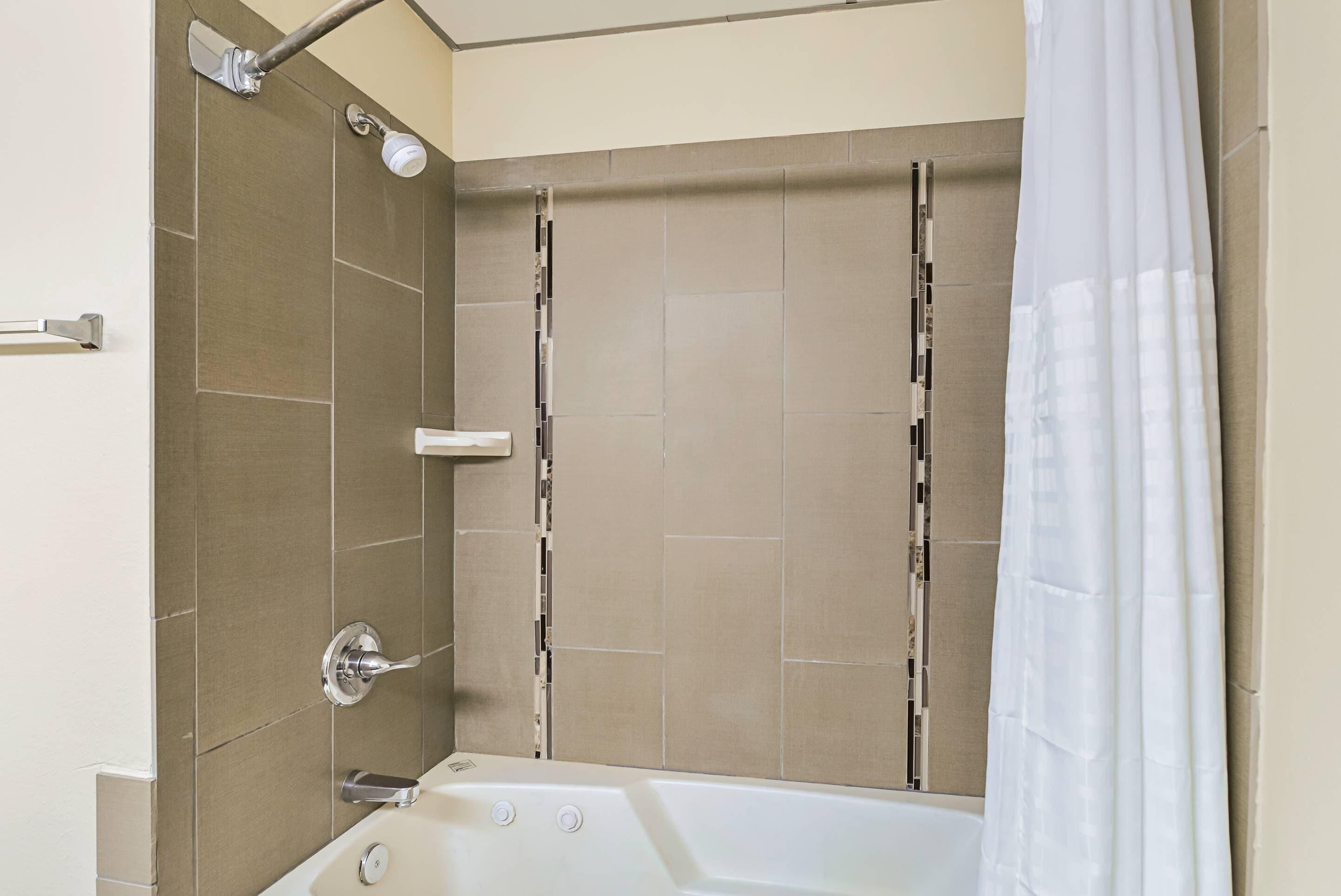 Une salle de bain moderne équipée d’une baignoire, d’une douche et d’un porte-serviettes.