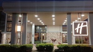 Une entrée d'hôtel moderne, dotée d'une enseigne lumineuse bien visible, d'un espace d'entrée abrité et d'une façade en pierre.