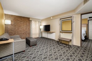 Una habitación de hotel con sofá, una mesita, televisión y espejo.