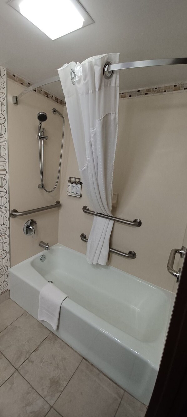 Une salle de bain équipée d’une baignoire, d’une douche et d’une barre d’appui.