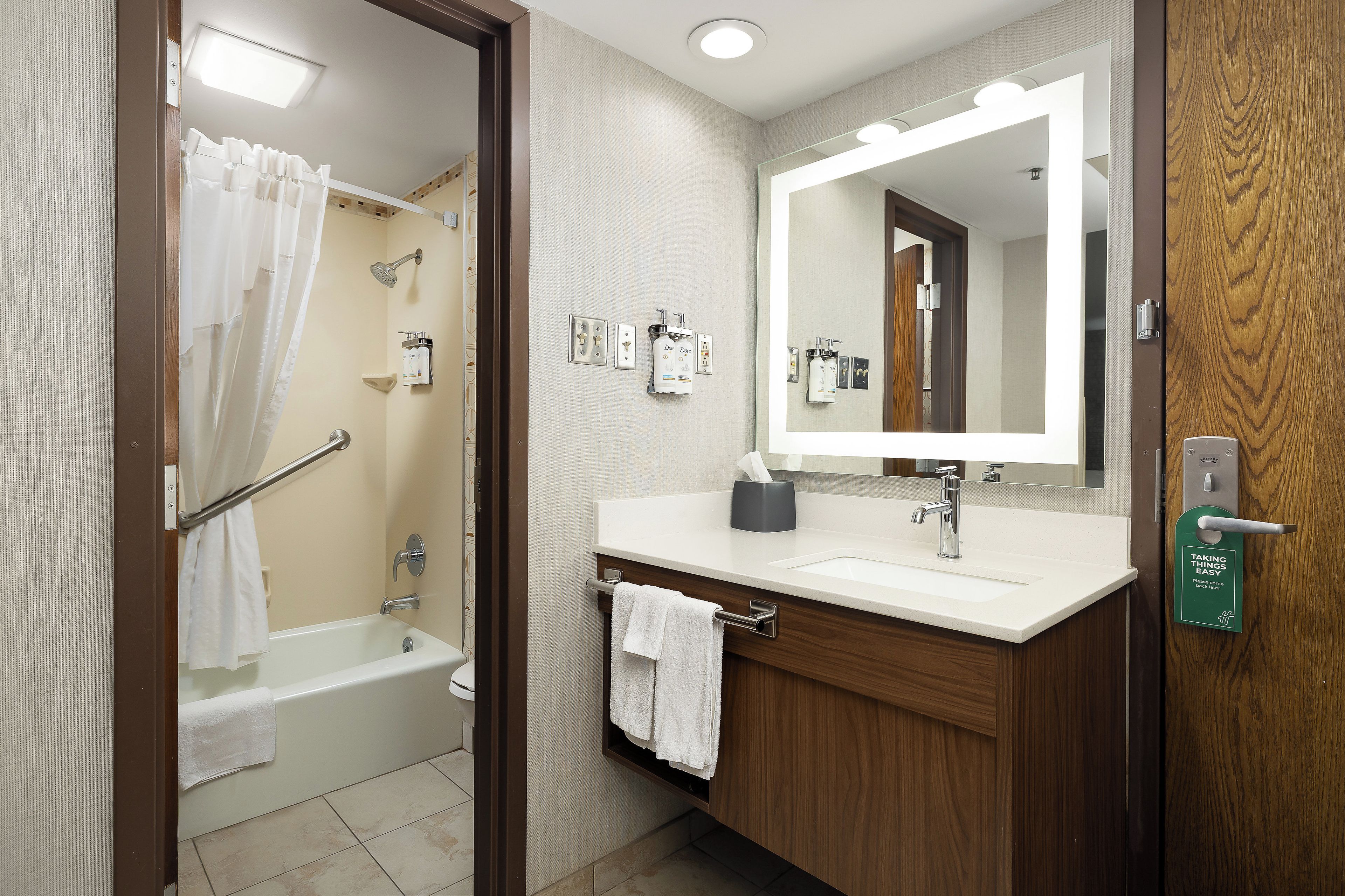 A bathroom with a bathtub, a sink, a mirror, and a towel rack.