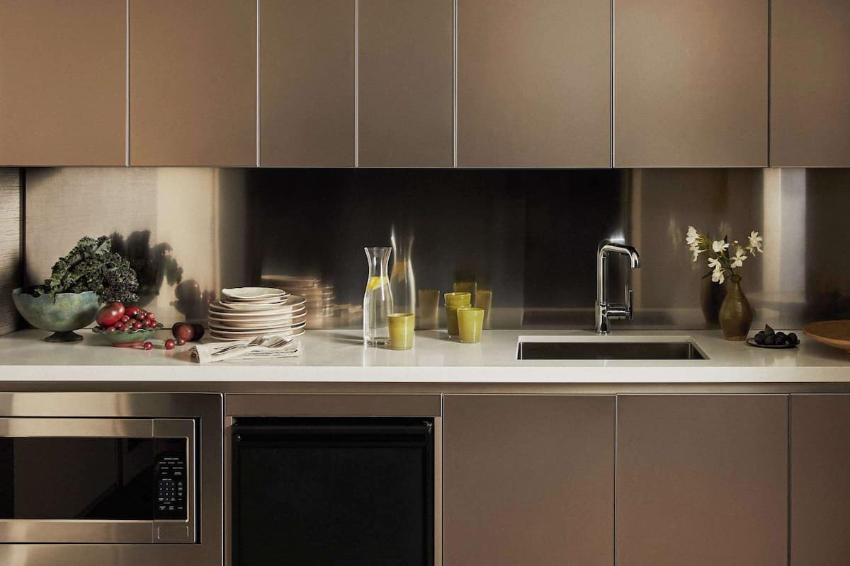 A modern kitchen with stainless steel appliances, a sink, and a countertop with various items.