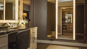 A modern bathroom with a large mirror, a vanity with a sink, and a chair. - L'Ermitage Beverly Hills (Beverly Hills)