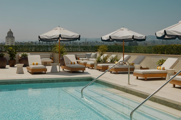 Una piscina al aire libre, camas de piscina con cargo, sombrillas