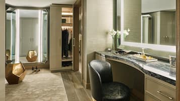 Un baño moderno con tocador, espejo y vestidor.