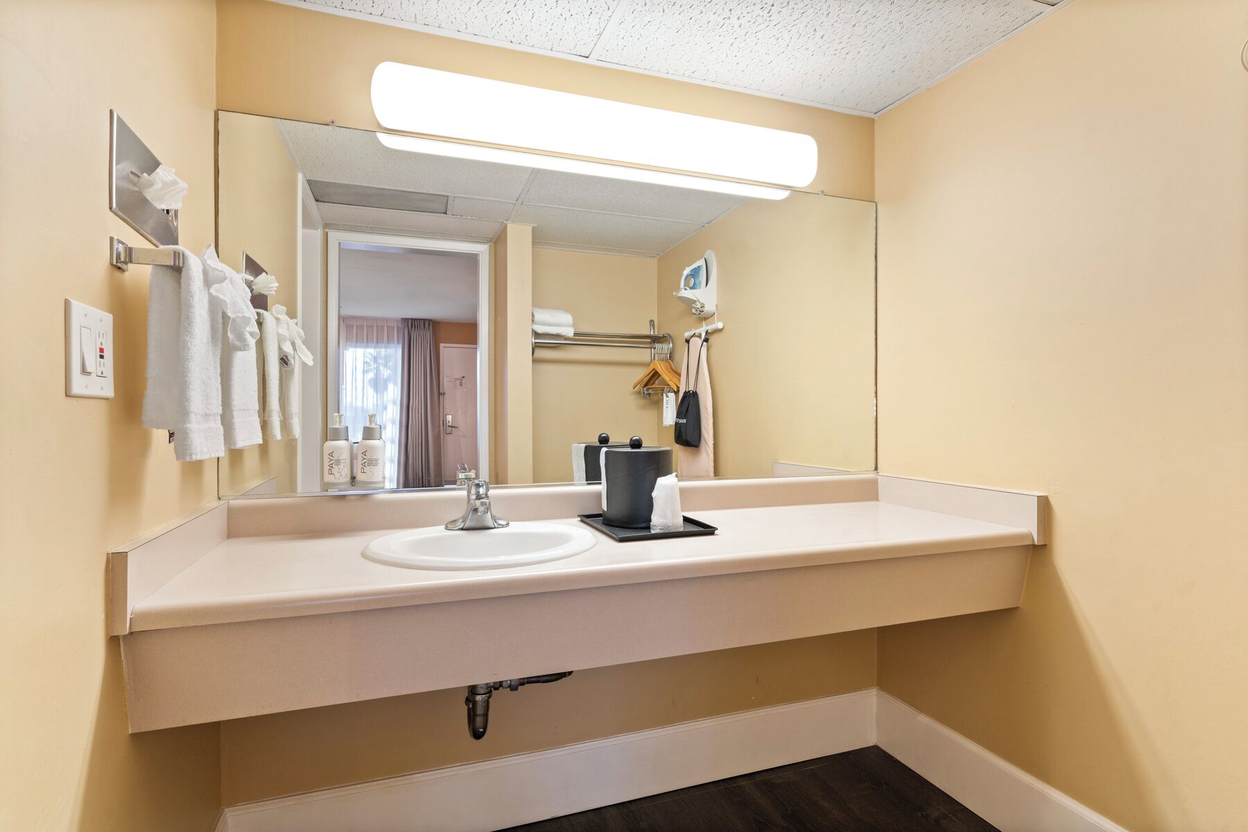 A bathroom with a white sink, a mirror, and a towel rack.