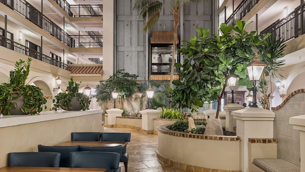 Un vaste espace intérieur aménagé avec différents types de sièges, notamment des tables et des chaises, le tout entouré d’une végétation luxuriante et d’un éclairage décoratif.